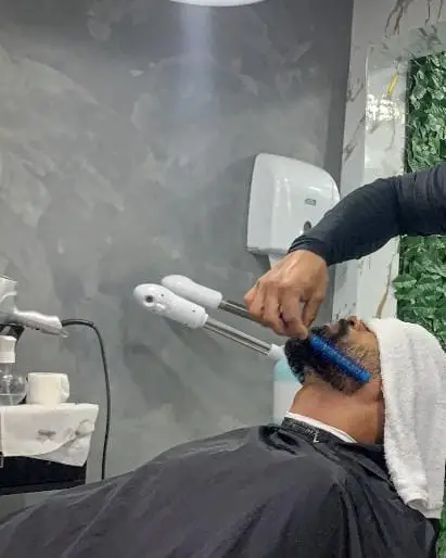 Barbeiro da GN3 finalizando o corte de um cliente com toalha quente